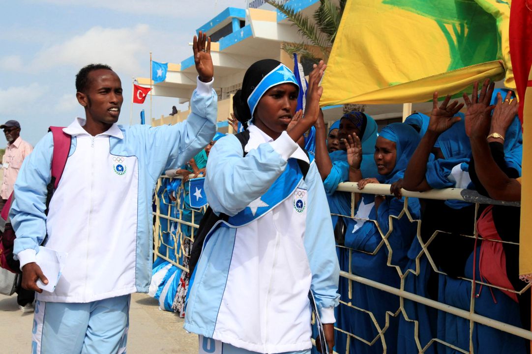 Mohamed Hassan (L) and Zamzam Farah, Somalia's representatives to the 2012 Olympics wave as they depart from the Aden Abdulle International Airport in Somalia's capital Mogadishu, July 17, 2012. Rarely able to travel to international meets, no Somali athlete qualified for the London Games outright. Each national Olympic committee is eligible for two guaranteed places -- one for a man, one for a woman -- in athletics. REUTERS/Feisal Omar (SOMALIA - Tags: SPORT ATHLETICS SOCIETY OLYMPICS)