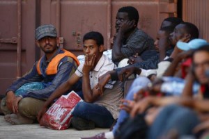 Rescued migrants sit on the ground at the Armed Forces of Malta Maritime Squadron base at Haywharf in Valletta's Marsamxett Harbour