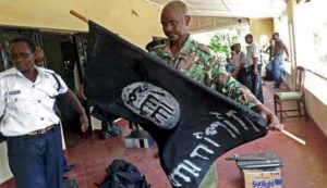 A Kenyan police officer folds up a flag inscribed with the logo of the Islamic state (IS) following a raid on two mosques in the coastal city of Mombasa, on November 17, 2014.  One man was killed  as Kenyan security forces arrested over 200 people and seized weapons in raids on mosques accused of links with Somalia's Al-Qaeda affiliated Shebab militants, police said. Security forces began the operation in the early hours of Monday morning, targeting the Masjid Musa and Sakina mosques in the port city of Mombasa. AFP PHOTO/STR        (Photo credit should read STRINGER/AFP/Getty Images)